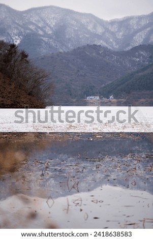 Scenery of snow-capped mountains reflected in a half-frozen river Royalty-Free Stock Photo #2418638583
