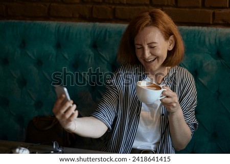 Freelance joy a red-haired smiling woman takes a selfie during a coffee break.
