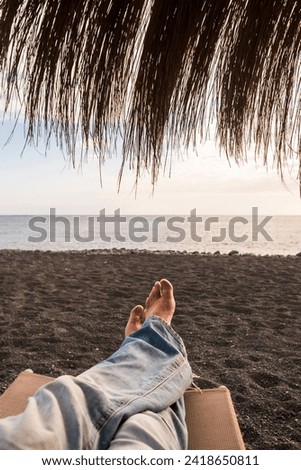 Concept of summer holiday travel vacation with point of view of man feet relaxing and enjoying the beach and the sun looking at the sea and relaxing