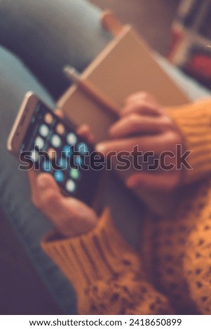 Closeup of woman viewed from above using a smart phone at home for work or social media sharing life activity - focus on eyeglasses and defocused background - yellow colors