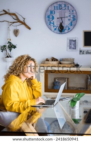 Adult blonde woman at home work with computer laptop and internet connection -concept of technology activity and smart job with modern people - lockdown quarantine for covid-19 Royalty-Free Stock Photo #2418650941