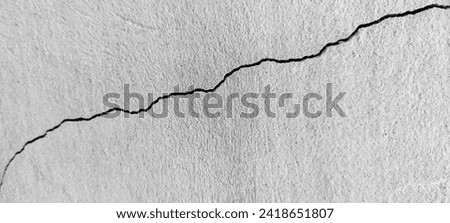 Big long curve diagonal ascending crack on old plastering wall. Copy space. Black and white photo. Selective focus. Royalty-Free Stock Photo #2418651807