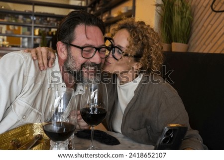 Happy couple smiling and talking in a restaurant drinking red wine - Married couple having lunch break at cafe bar - Lifestyle concept with man and a woman going out on weekend day Royalty-Free Stock Photo #2418652107