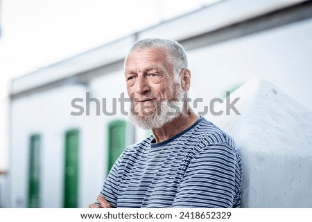 75 year old senior man laughs while having a good time outdoors. Royalty-Free Stock Photo #2418652329