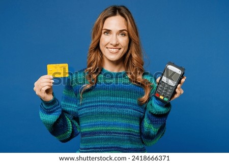 Young woman she wears knitted sweater casual clothes hold wireless modern bank payment terminal to process acquire credit card isolated on plain blue cyan color background studio. Lifestyle concept