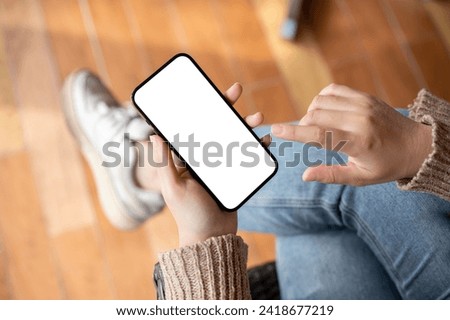 Close-up top view image of a woman using her smartphone while sitting indoors, chatting or reading an online blog. a white-screen smartphone mockup. People and technology concepts