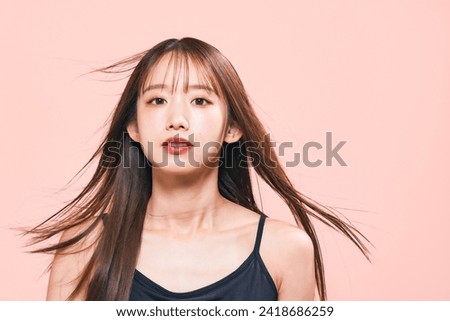 Young Asian woman blowing by wind her hair. Beauty, hair care and cosmetics concept. Royalty-Free Stock Photo #2418686259