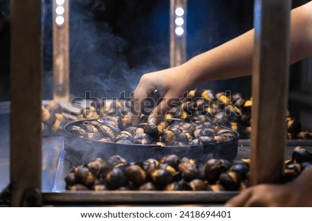Close-up of the chestnut seller's hand roasting chestnuts outdoors on Istiklal Street