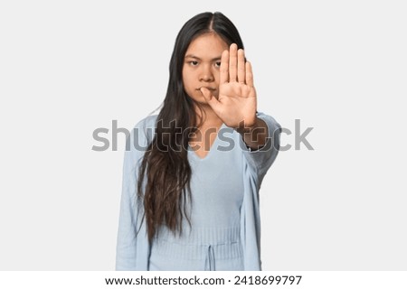 Young chinese woman isolated standing with outstretched hand showing stop sign, preventing you.