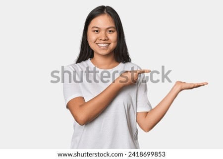 Young chinese woman isolated excited holding a copy space on palm.