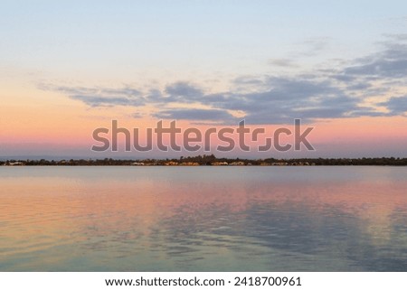 Twilight sky over estuary with urban background. Royalty-Free Stock Photo #2418700961