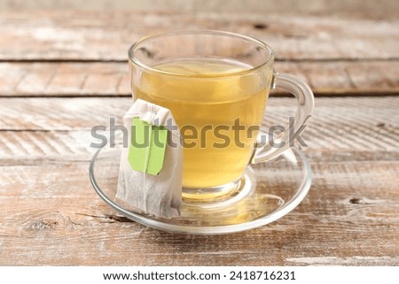 Tea bag in glass cup on wooden table, closeup
