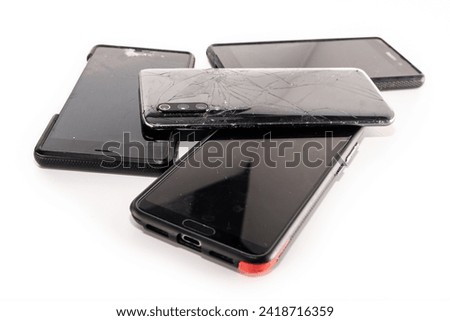 Pile of broken smartphones isolated on white background. Damaged mobile phones with cracked screen.