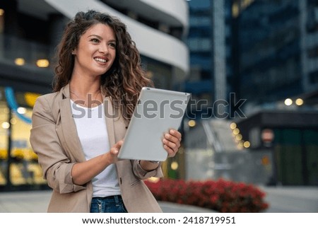 Stylish young businesswoman using digital tablet in downtown financial district in the city.