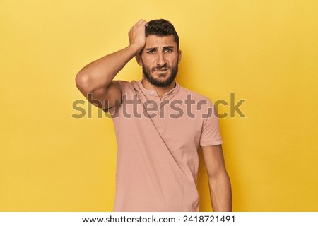 Young Hispanic man on yellow background tired and very sleepy keeping hand on head.