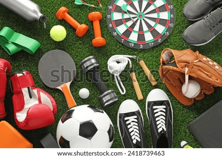 Different sport equipment and sneakers on green grass, flat lay Royalty-Free Stock Photo #2418739463