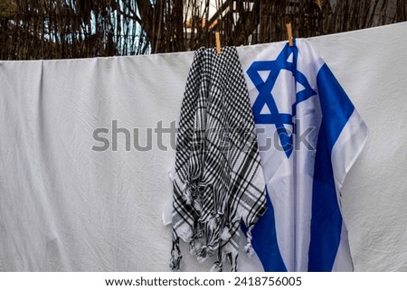 Israel flag and Palestinian scarf together lying on a rope to dry after washing or lying on a surface Royalty-Free Stock Photo #2418756005