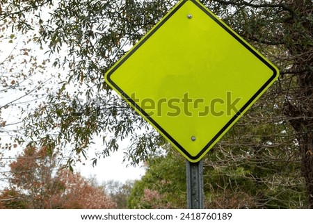 Blank fluorescent green triangular yield sign with trees in the background
