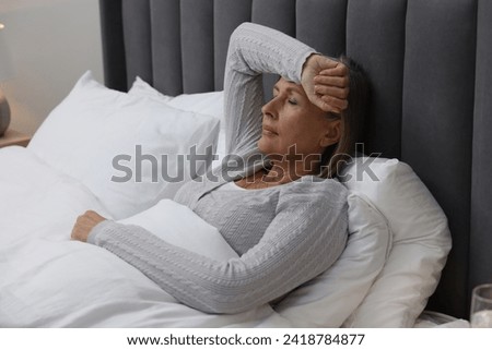 Menopause. Woman suffering from headache in bed indoors Royalty-Free Stock Photo #2418784877