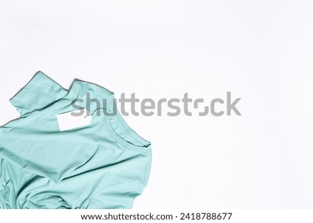 Minimalism style composition with blue t-shirt with empty white tag on white background with copy space for your design top view.
