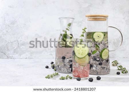 The concept of detox diet and body cleansing. Refreshing homemade lemonade cocktail with fresh cucumbers, blueberries and mint. Fruit juice and ingredients, weight loss concept,