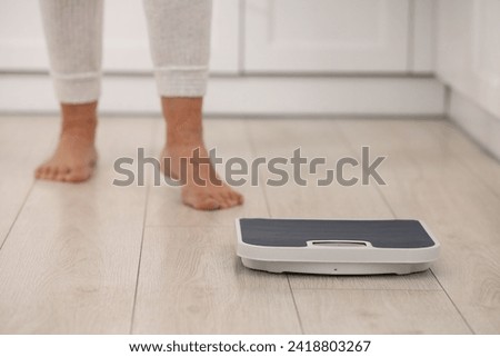 Menopause, weight gain. Woman standing on floor indoors, focus on scales Royalty-Free Stock Photo #2418803267