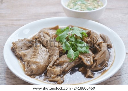 chop boiled duck wing and stew intestine in brown soy soup on plate dipping spicy sauce 