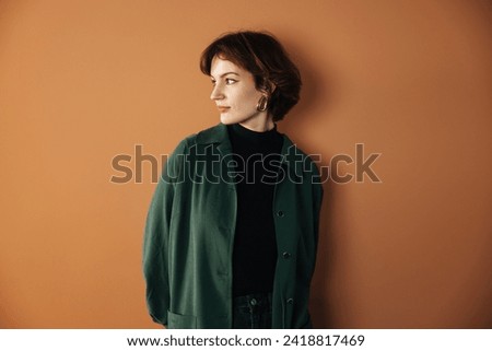 A self-assured young woman confidently strikes a pose in her recently acquired, contemporary apartment. The headshot captures a millennial female  Royalty-Free Stock Photo #2418817469