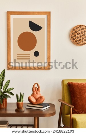 Minimalist composition of living room with brown mock up picture frame, plant, retro armchair, dried tropical leaf, decoration and elegant personal accessories in stylish home decor. Template.