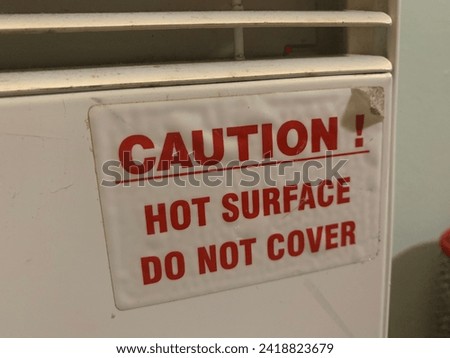 Grungy sticker "Caution Hot Surface Do Not Cover" Up close picture attached to an electric heater