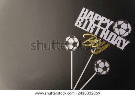 Happy birthday poster for the boy on a horizontal black background with text and a soccer ball symbol. Place the main object in the empty space on the left side of the image.