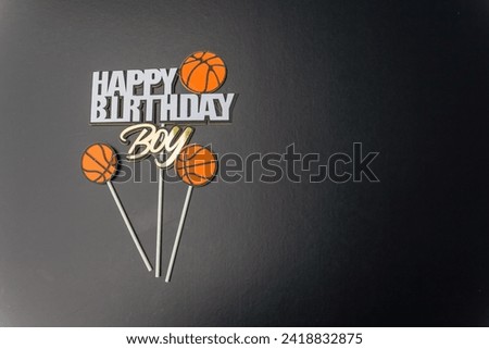Happy birthday poster for boy on horizontal black background with text and basketball symbol. Place the main object in the empty space on the left side of the image.
