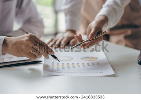 Teamwork with business people analyzing cost graphs on a table at a business conference room and office workers working with project planning documents on a conference table, close-up photography
