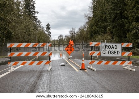 Signs and cones at a road barricade. Street of HIllsboro closed due to high water after a rainfall 