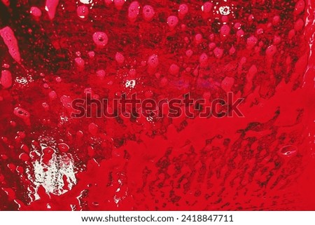 

The vibrant texture of a red splash of suds on a car window at a drive thru car wash.