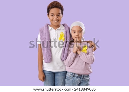 Cute little children with yellow ribbons on lilac background. Childhood cancer awareness concept Royalty-Free Stock Photo #2418849035