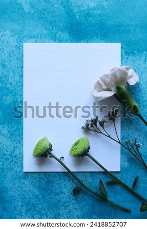 a white card with flowers on a blue background
