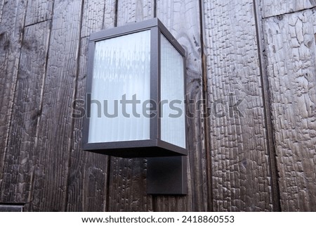 Modern external lamp on burned wood wall Royalty-Free Stock Photo #2418860553