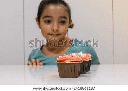 Girl smiling in the background wanting to eat homemade cupcakes 