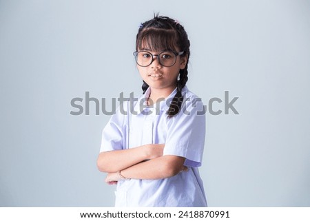Girl in Thai school uniform,Portrait lovely Asian student girl in Thai school uniform pointing finger up isolated on pink background.