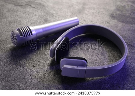 Microphone and headphones on grey textured table, closeup. Sound recording and reinforcement