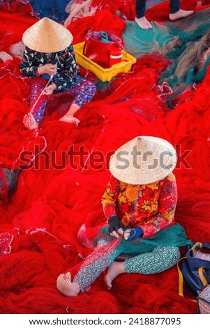 Fisherman casting their net at the boat. Traditional fishermen prepare the fishing red net. Focused bearded male fisher with red fish in net during traditional fishing in Tan Long, My Tho city