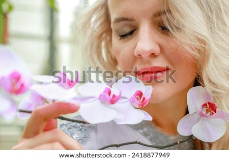 A woman's face is close to a pink archidea. The scent of flowers. Femininity concept