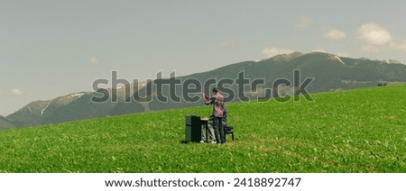 Piano player in a field landscape. Grass. Young pianist
