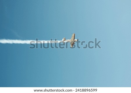  A small plane in a blue sky with a contrail. High quality photo