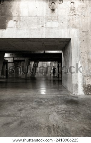 An indoor concrete corridor for urban exploration, creating an industrial brutalist walkway with no people and rough textures. Neutral colour palette with copy space for web design or background Royalty-Free Stock Photo #2418906225