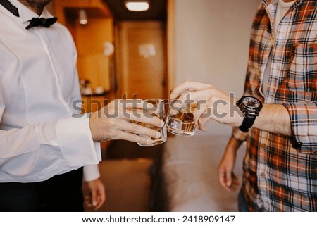 Whiskey glasses clinked in the groom's room before the ceremony. stock photo