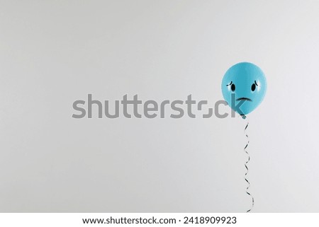 Light blue balloon with sad face on grey background. Space for text