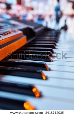 Close-up of piano keys with blurred silhouettes of people in background. Promotional material for community outdoor piano project. Concept of music instruments, performance, hobby, art, entertainment