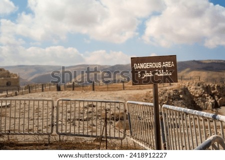 Dangerous area sign with barricades and arabic writing in the middle east. stone path scene with warm tones
